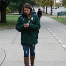 A student looks down at her phone while walking to class.